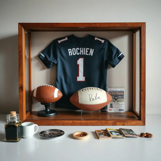 Wood display case holding framed jersey, signed football, and vintage memorabilia cards.