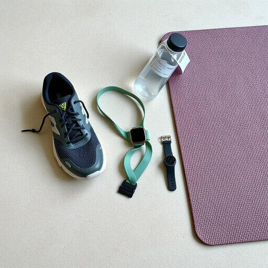 Training essentials laid out neatly: shoes, resistance band, watch, water bottle, and recovery tool