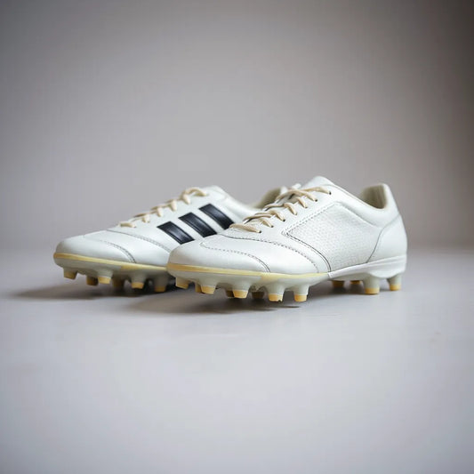 Premium soccer shoes with visible stitching and studded outsole on a clean neutral background
