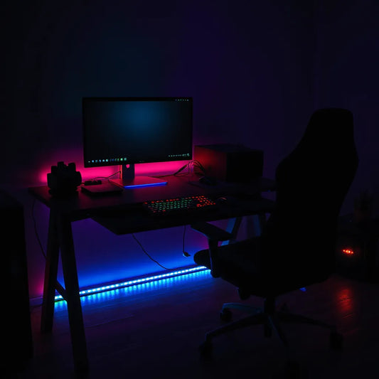 Gaming desk at night with RGB LED lighting under the keyboard and monitor