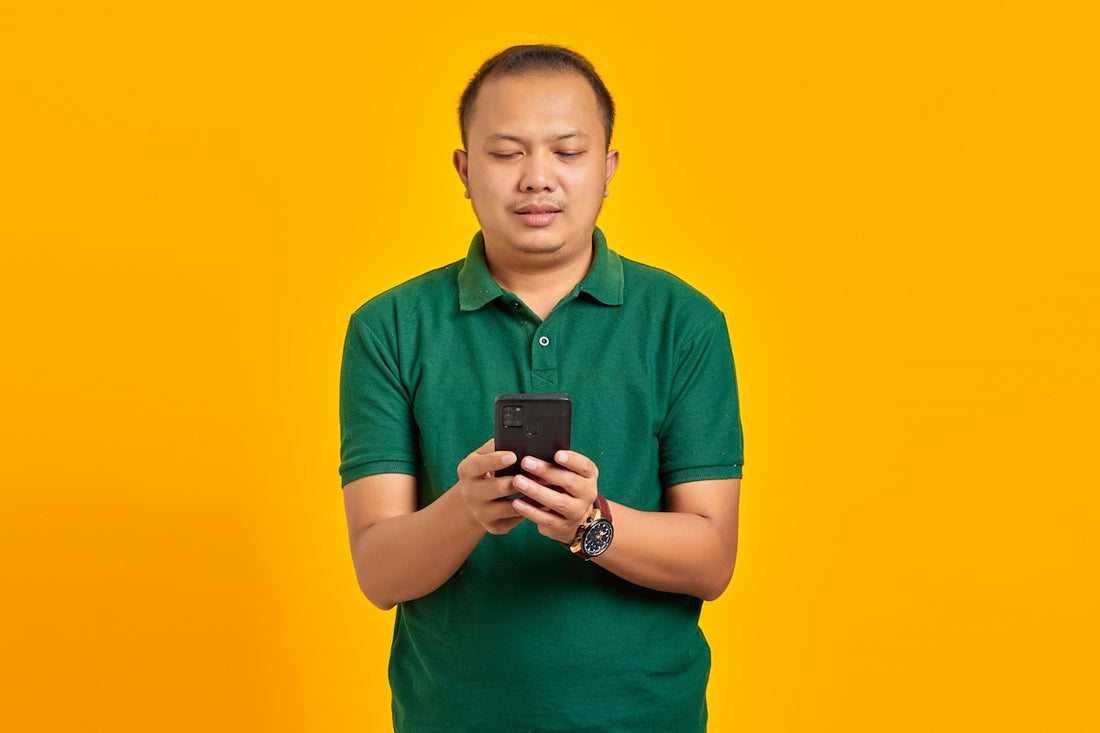 a man in a green shirt looking at a cell phone