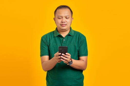 a man in a green shirt looking at a cell phone