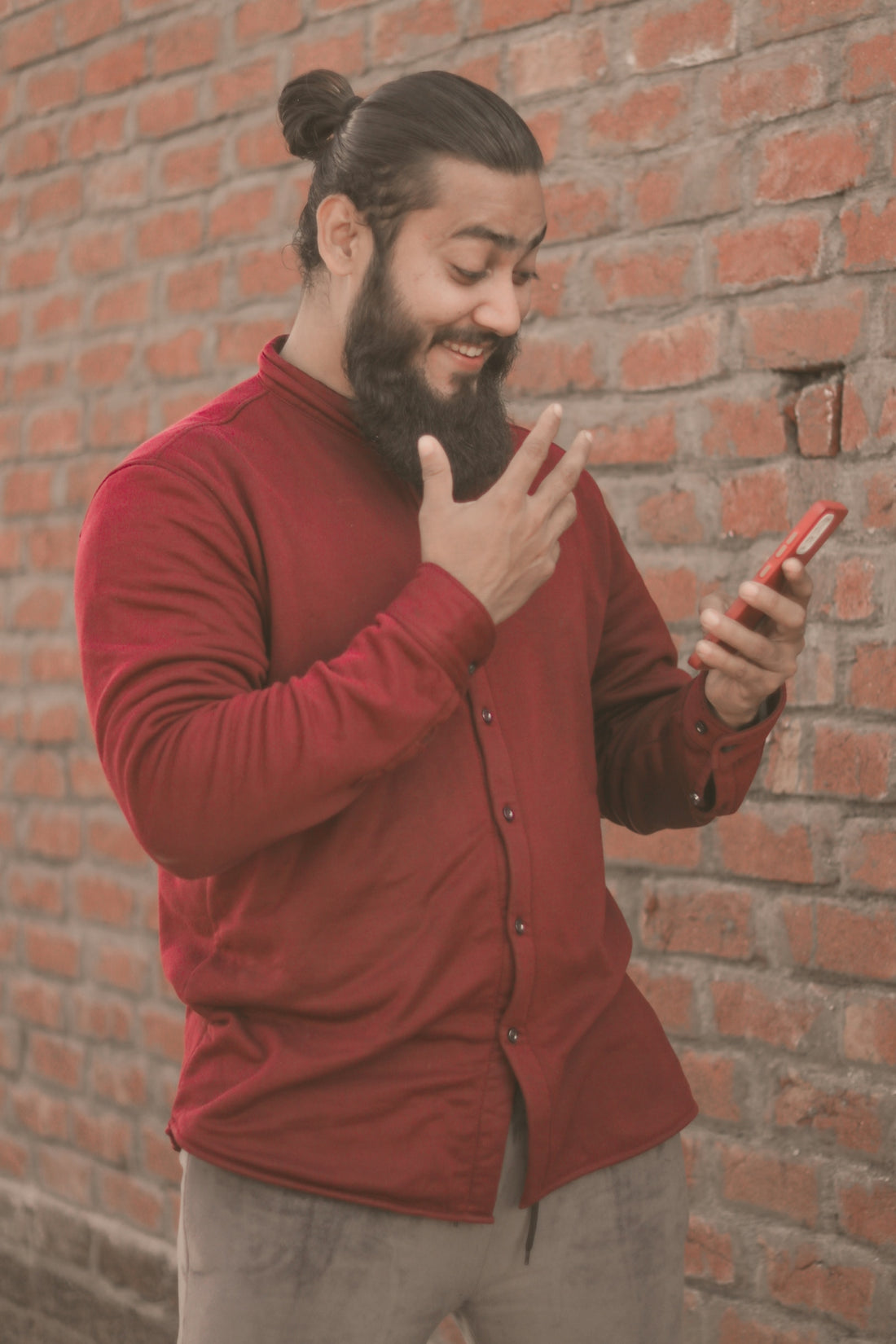 a man with a beard pointing at a cell phone