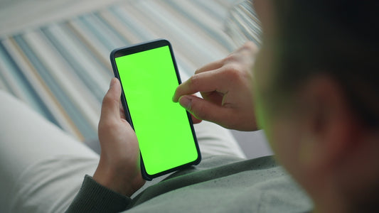 Person holding a smartphone with a green screen