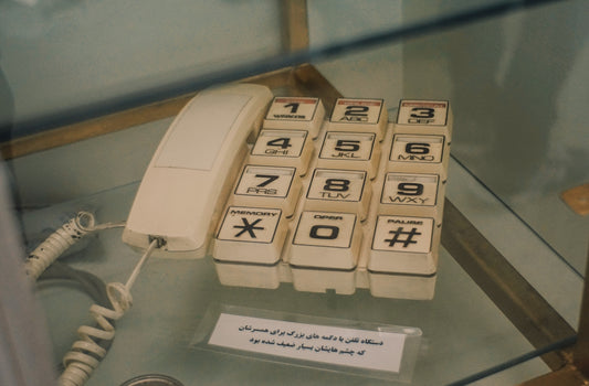 A vintage white telephone with a coiled cord.