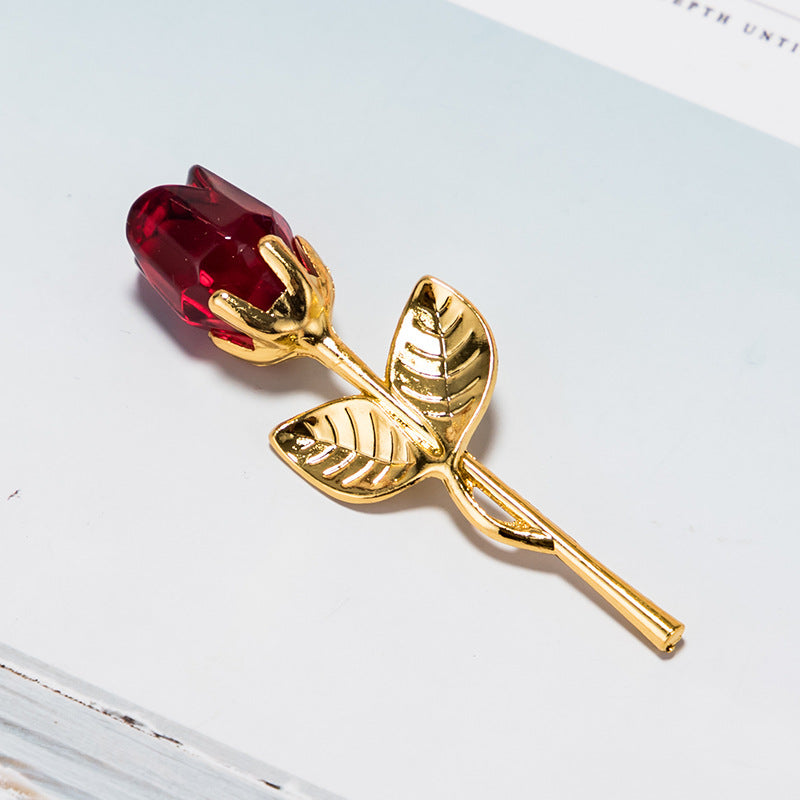 A Valentines Day gift crystal glass rose brooch with golden petals and a red crystal glass center resting on a white surface, perfect as a Valentine's Day gift from Sammy Sk Football.